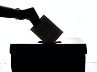 Hånd der stikke stemmeseddel ned i en valgkasse
