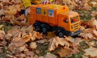 Dreng sidder i blade og leger med orange skraldebil
